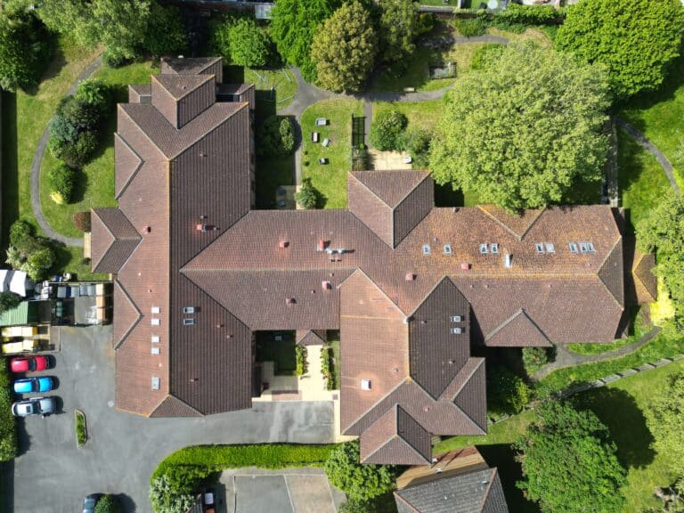 Aerial view of a complex brick building surrounded by trees