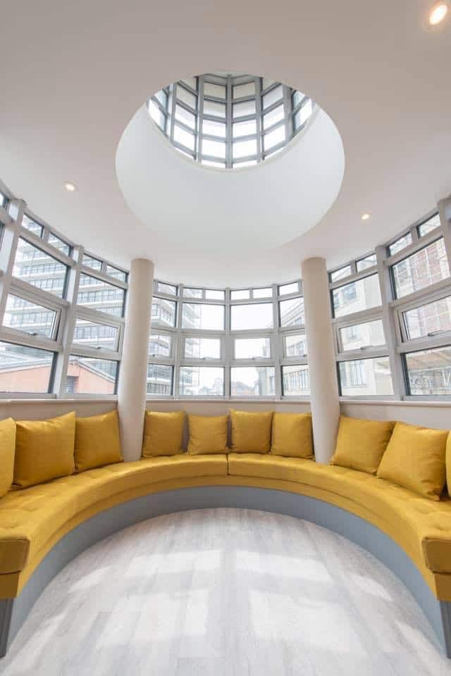 Modern atrium with skylight and yellow circular sofa